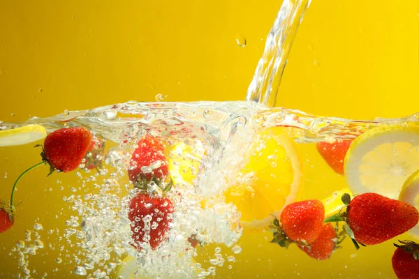 Stock image Fruits in water against yellow background, concept of freshness