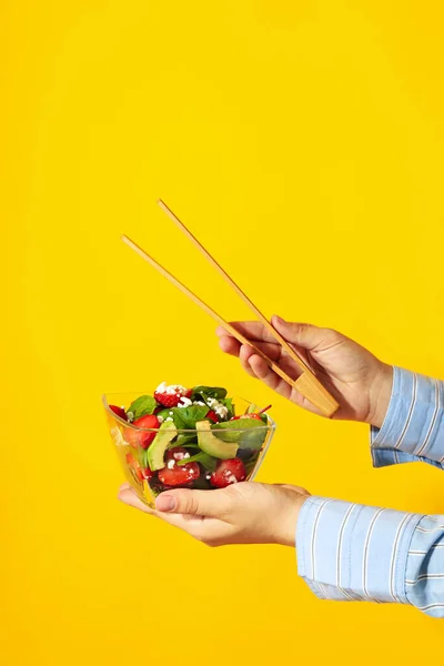 Vrouwelijke Handen Houden Salade Met Aardbei Tang Gele Achtergrond — Stockfoto