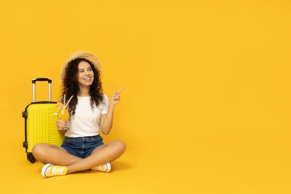 Young woman with suitcase on yellow background