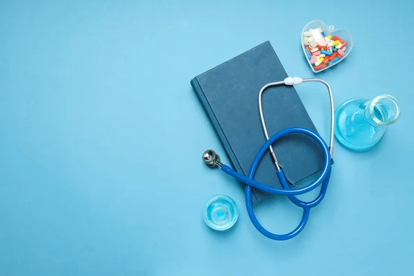 Medical literature - book and doctors accessories on blue background