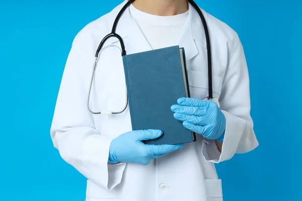 Female doctor holds book on blue background