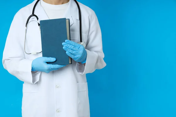 Female doctor holds book on blue background