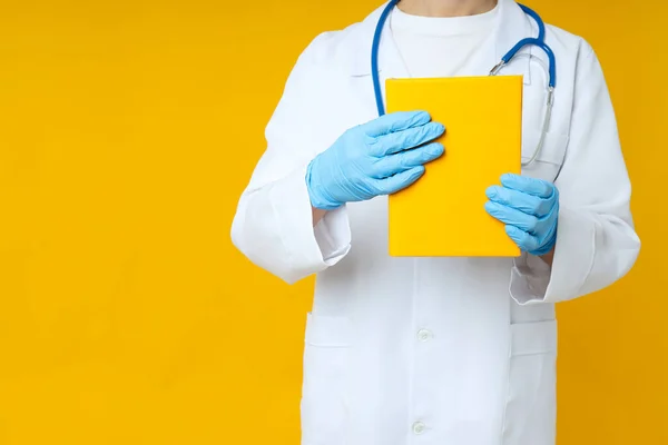 Female doctor holds yellow book on yellow background