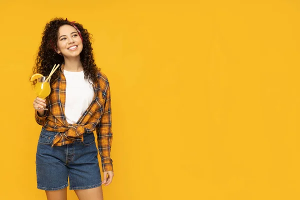 stock image Young woman with cocktail on yellow background