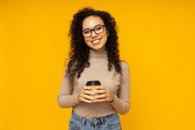 Sarı arka planda gündelik giyinmiş genç bir kadın.