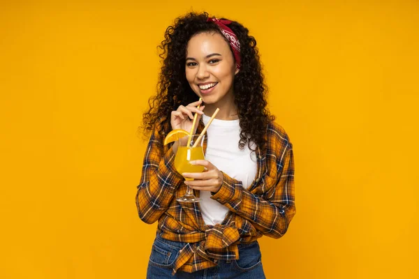 Young woman with cocktail on yellow background