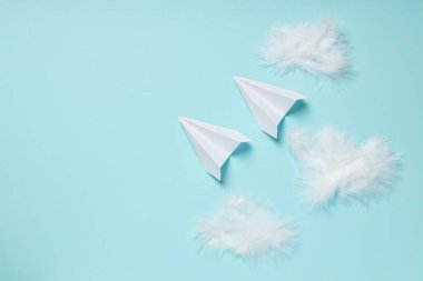 Mavi arka planda kağıt uçaklar ve tüyler