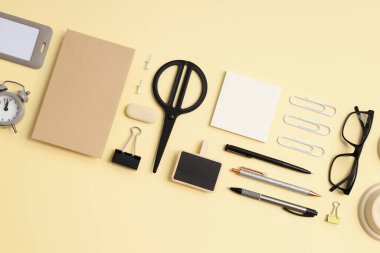 Bej arka planda farklı ofis aksesuarları olan düz maket.