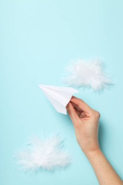 Kağıt uçaklı ve mavi arka planda tüyleri olan bir kadın.
