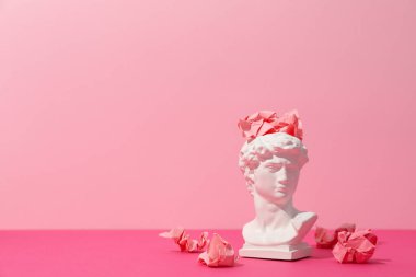 Pembe arka planda kağıt topları olan kadim kafa.
