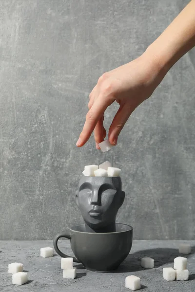 Cup with decorative head and sugar on gray background