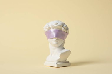 Bej arka planda gözleri kurdeleli kadim bir kafa.