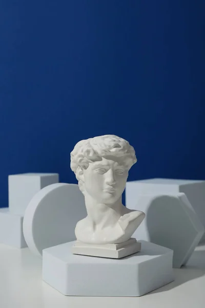 Γεωμετρικές Μορφές Και Αρχαία Κεφαλή Λευκό Τραπέζι Μπλε Φόντο — Φωτογραφία Αρχείου