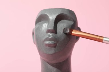 Pembe arka planda makyaj fırçası olan dekoratif kafa