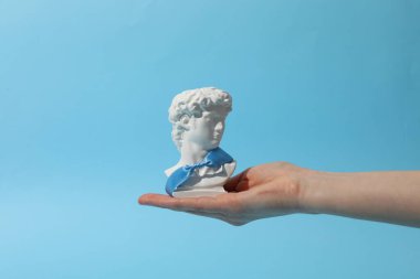 Kadın eli mavi arka planda antik kafayı tutuyor