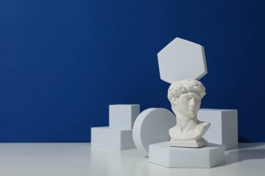 Geometrik şekiller ve antik kafa beyaz masada mavi arkaplanda