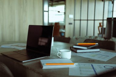 Kahve, dizüstü bilgisayar ve ofis kağıtları olan ofis masası, not defterleri.