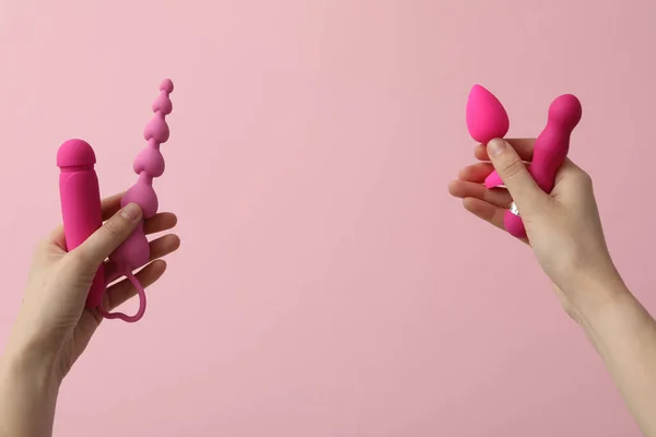 stock image A collection of pink sex toys on a pink background in hands