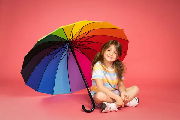 Ένα Κοριτσάκι Κάθεται Κάτω Από Μια Πολύχρωμη Ομπρέλα — Φωτογραφία Αρχείου