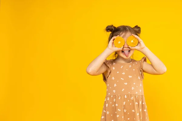Een Meisje Met Sinaasappels Bij Haar Ogen Een Gele Achtergrond — Stockfoto