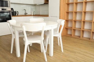 Mutfakta sandalyeleri olan yuvarlak, beyaz bir masa.