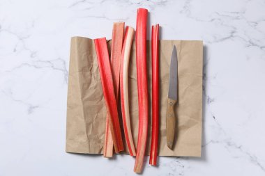 Rubarb ve bıçak kağıt üzerinde, beyaz mermer arka plan, üst manzara