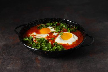 Shakshuka, arka planda kızartma tavasında.