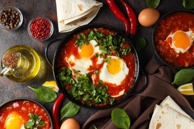 Shakshuka, yumurta, fesleğen, koyu arka planda bir kase biber ve yağ, üst manzara