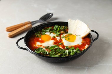 Shakshuka ve Pita tavada, kaşık ve çatal arka planda, kapat