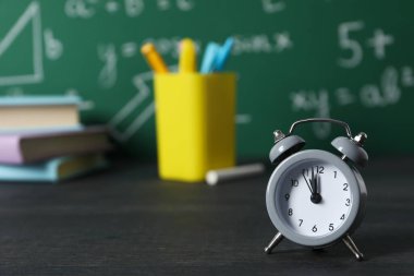 Okul malzemelerinin arka planındaki masanın üzerindeki saat.