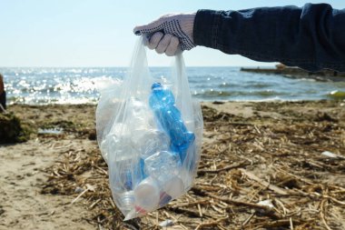 İnsanlar nehrin kıyısındaki çöpleri temizliyor, çevreyi koruyor.