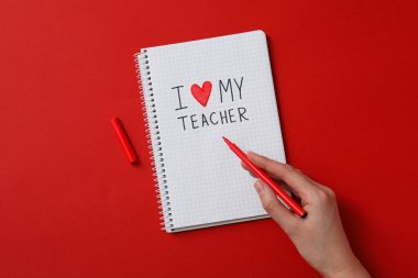 Kırmızı arka planda işaretli not defteri ve kadın eli