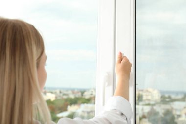 Bir kadının eli şehir manzaralı bir pencere açar.