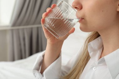 Genç bir kadın yakın plan bir bardaktan su içiyor.