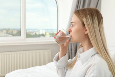 Genç bir kadın yakın plan bir bardaktan su içiyor.