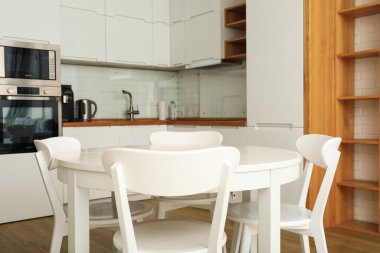 Mutfakta sandalyeleri olan yuvarlak, beyaz bir masa.