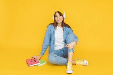 Sarı arka planda kulaklıklı çekici bir genç kadın.