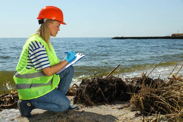 stock image A woman in a hard hat investigates river pollution