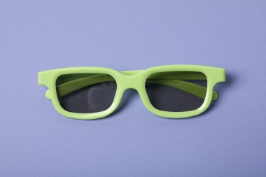 Mor arka planda renkli lensli yeşil gözlükler.