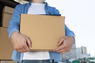 Kutuları olan bir arabanın yanında elinde kutu olan bir kurye.