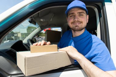 Gülümseyen bir kurye paketleri arabayla teslim eder.