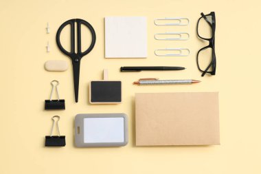 Gözlüklü kırtasiye modeli ve bej arka planda farklı kırtasiye malzemesi, üst görünüm