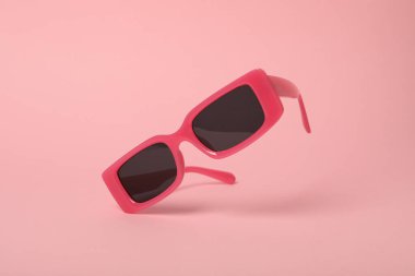 Pembe arka planda koyu lensli pembe gözlükler, yakın plan.