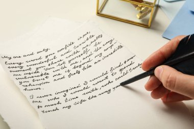 Beyaz arkaplanda yazı ve kuş tüyü bulunan mektup