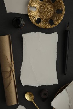 Kağıtlar, altın tabaklar ve kaşık, mürekkep şişesi ve kalem koyu gri arka plan, üst manzara