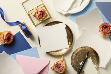 Kağıt parçaları, güller ve altın plakalar beyaz arka planda, üst manzara