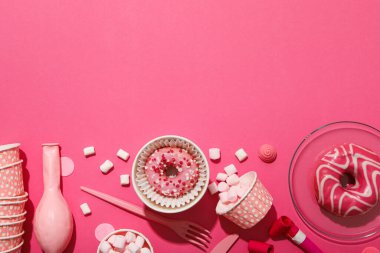 Donutlar, balonlar, kağıt bardaklar ve pembe arka planda şekerlemeler, metin için yer