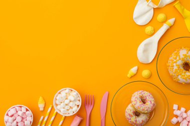 Donutlar, jöleli şekerler ve sarı arka planda parti malzemeleri, mesaj için yer