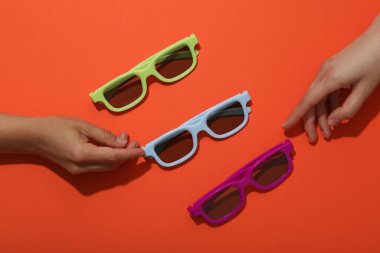 Güneş koruyucu, parlak turuncu arka planda renkli gözlükler.