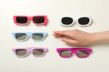 Beyaz arka planda eli olan bir yığın güneş gözlüğü.